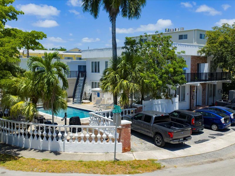 Street view of 105 NE 16th Terrace showing the swimming pool, palms and parking behind a white balustrade