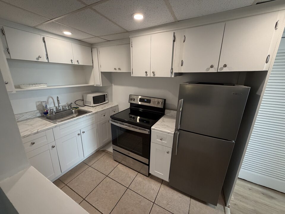 Kitchen with white cabinets, stainless steel refrigerator, range and microwave