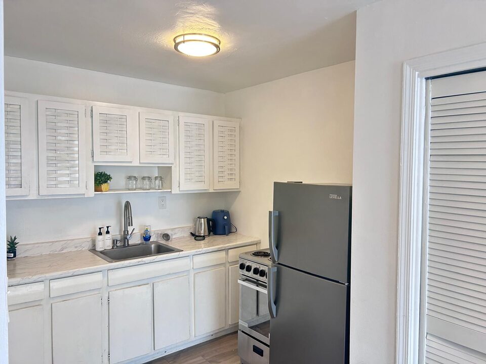 Kitchen with white cabinets, stainless steel refrigerator and electric range