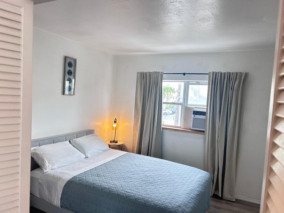 Bedroom with a curtained window, air conditioning unit and closet