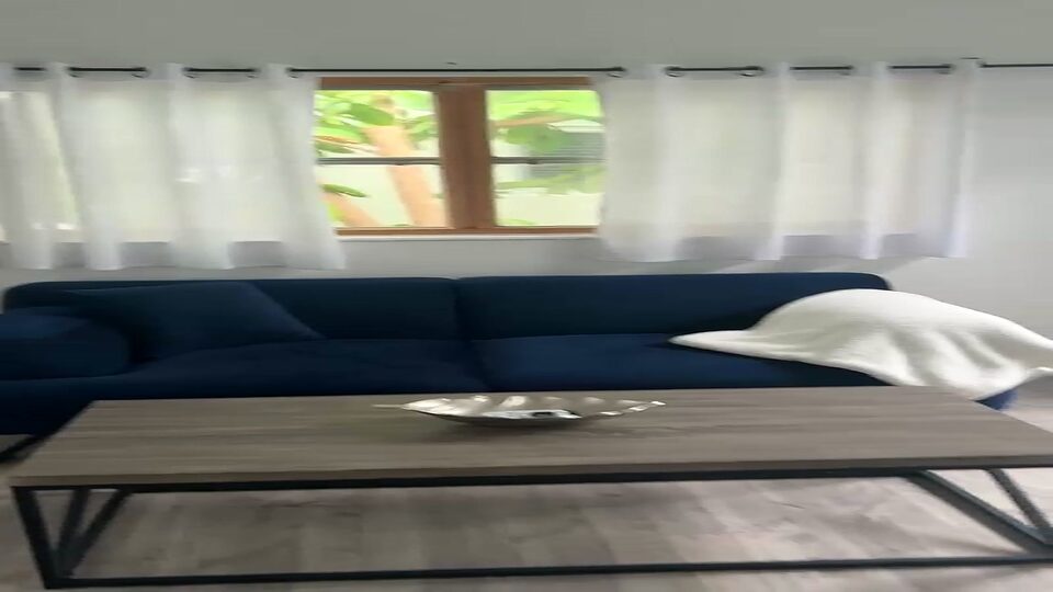 Living room with a navy sofa and coffee table beneath a curtained window