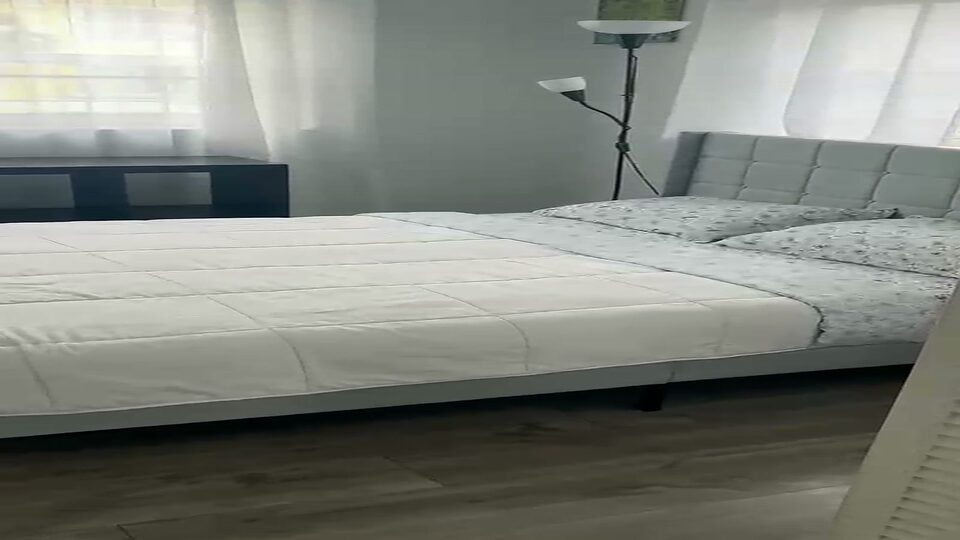 Bedroom with an upholstered headboard, floor lamp and plank flooring