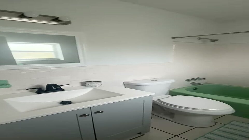 Bathroom with a white vanity, mirror and tub