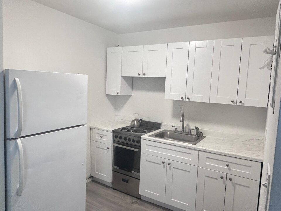 Kitchen with white shaker cabinets, a white refrigerator, a stainless steel electric range and a stainless steel sink in a marble-look countertop