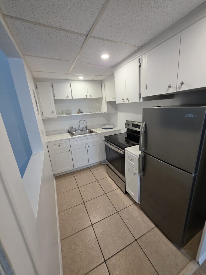 Kitchen with white cabinets, a marble-look countertop, a stainless steel sink, an electric range and a refrigerator