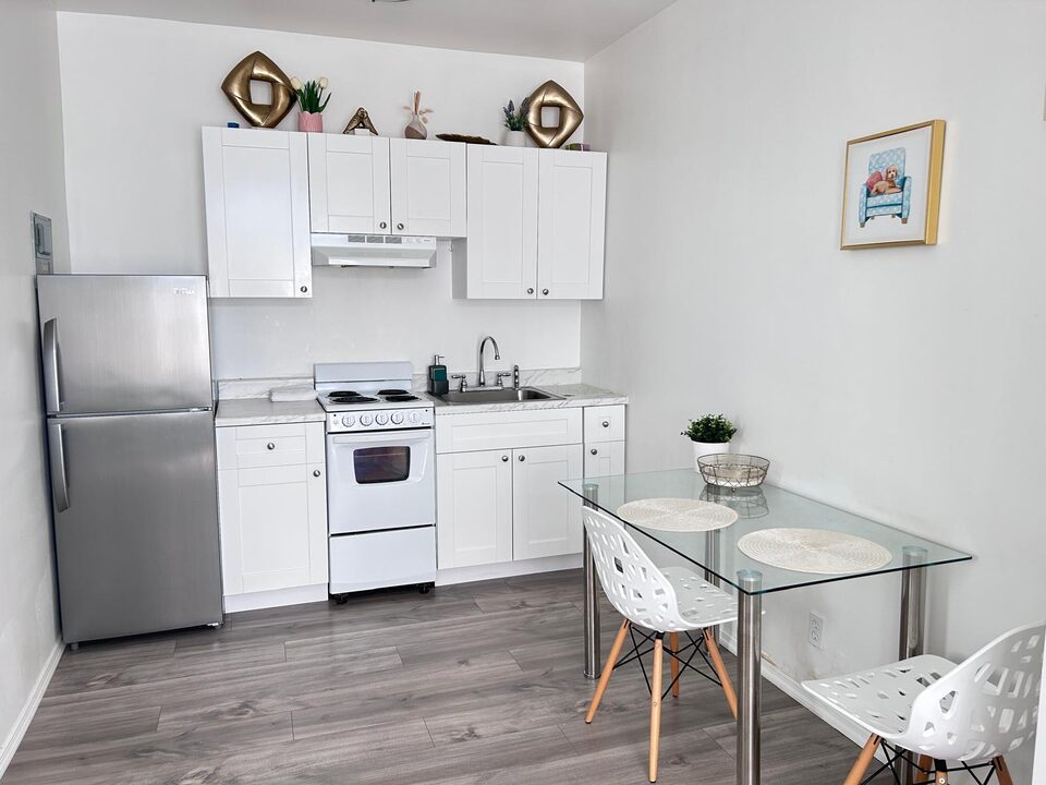 Kitchen with white shaker cabinets, stainless steel refrigerator, electric range and a glass dining table