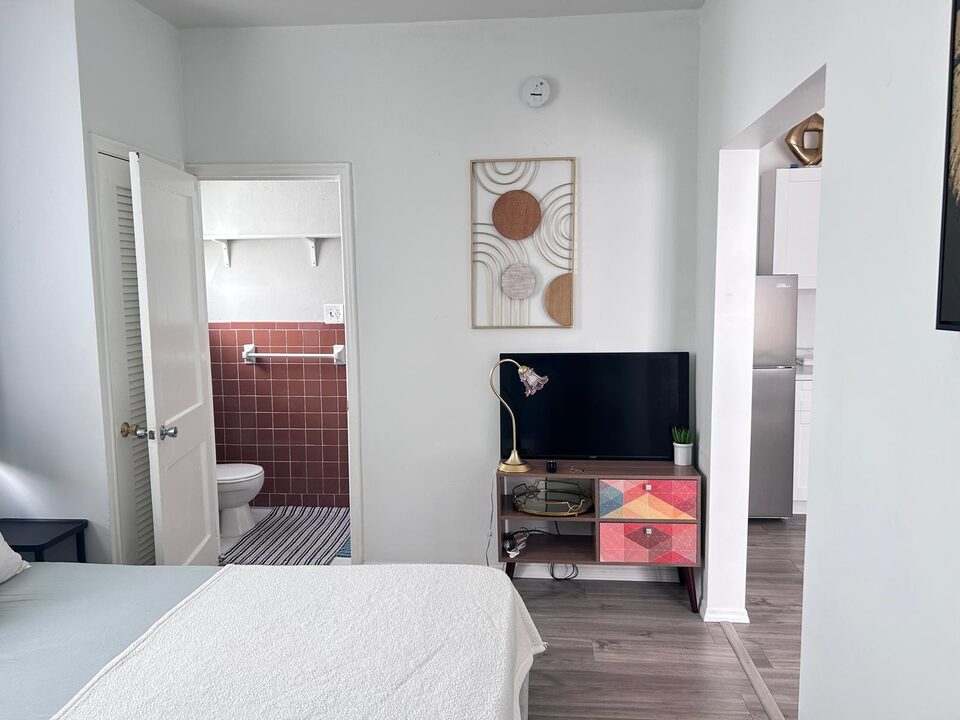 Living and sleeping area looking through to the kitchen, with a television on a painted console