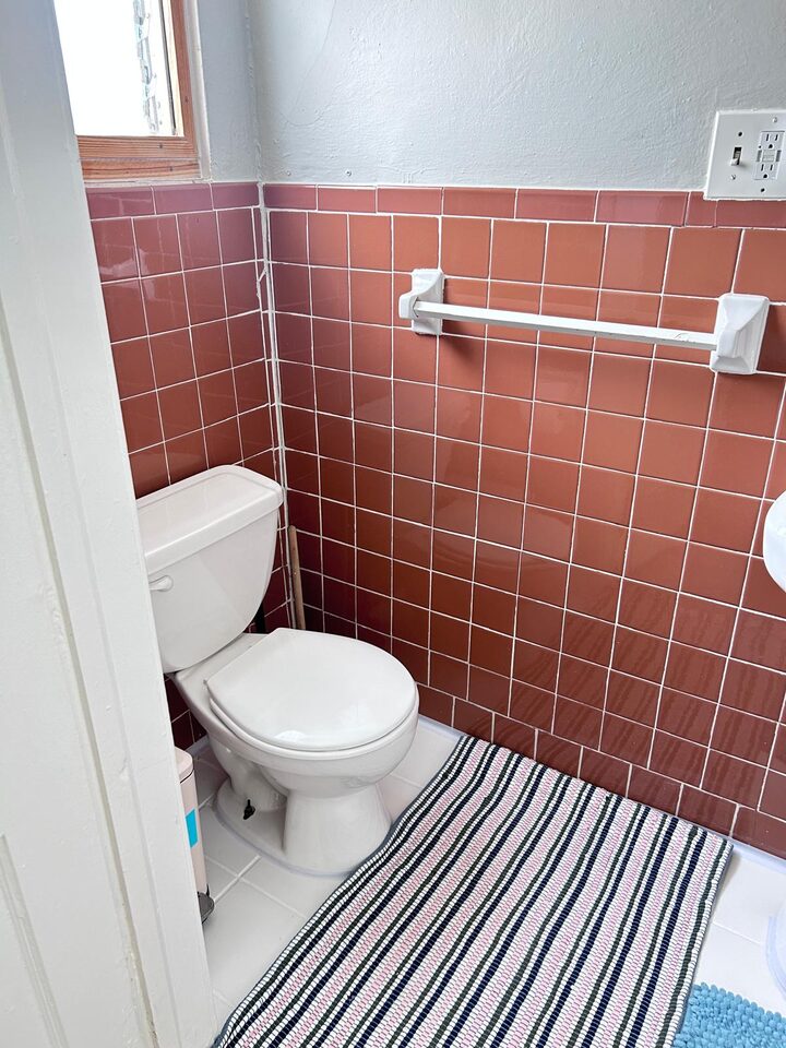 Bathroom with terracotta tiled walls, toilet and towel bar