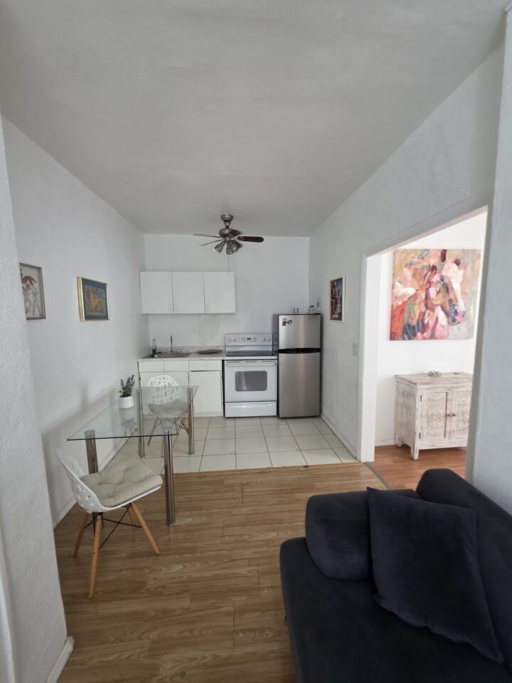 Kitchen and dining area with white cabinets, an electric range, a stainless steel refrigerator and a glass dining table