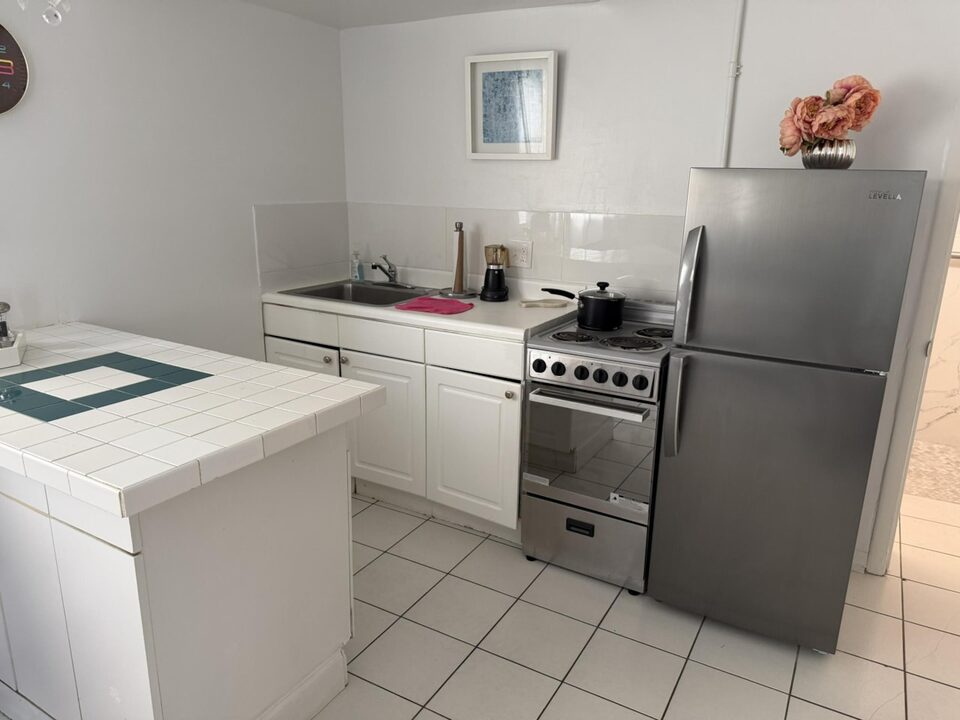 Kitchen with stainless steel refrigerator, electric range and tiled countertop