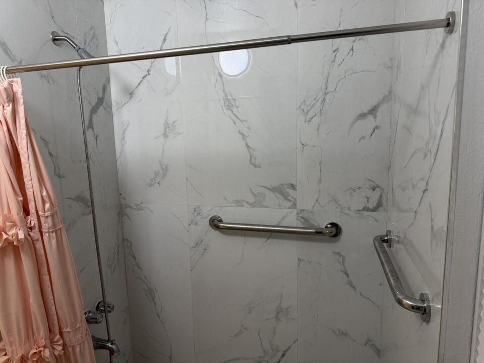 Bathroom with full-height marble-look tile shower and grab bar