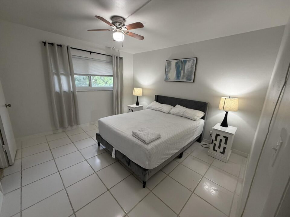 Bedroom with ceiling fan, bedside lamps and tile floors