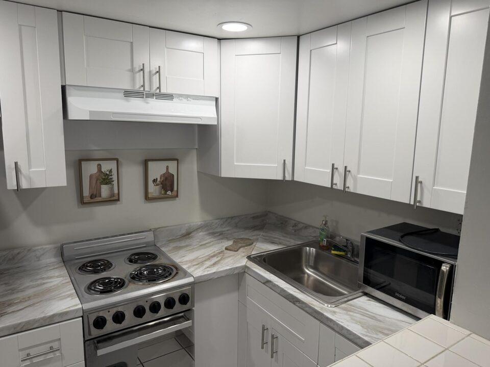 Renovated kitchen with white shaker cabinets, range and microwave