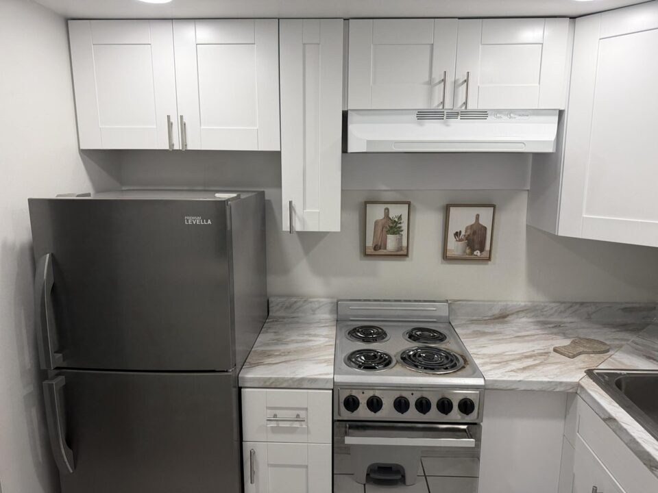Kitchen with white shaker cabinets, marble-look countertop, stainless steel refrigerator and electric range