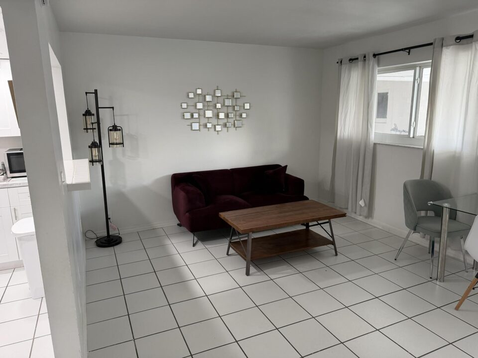 Living room with white tile floors and large curtained window