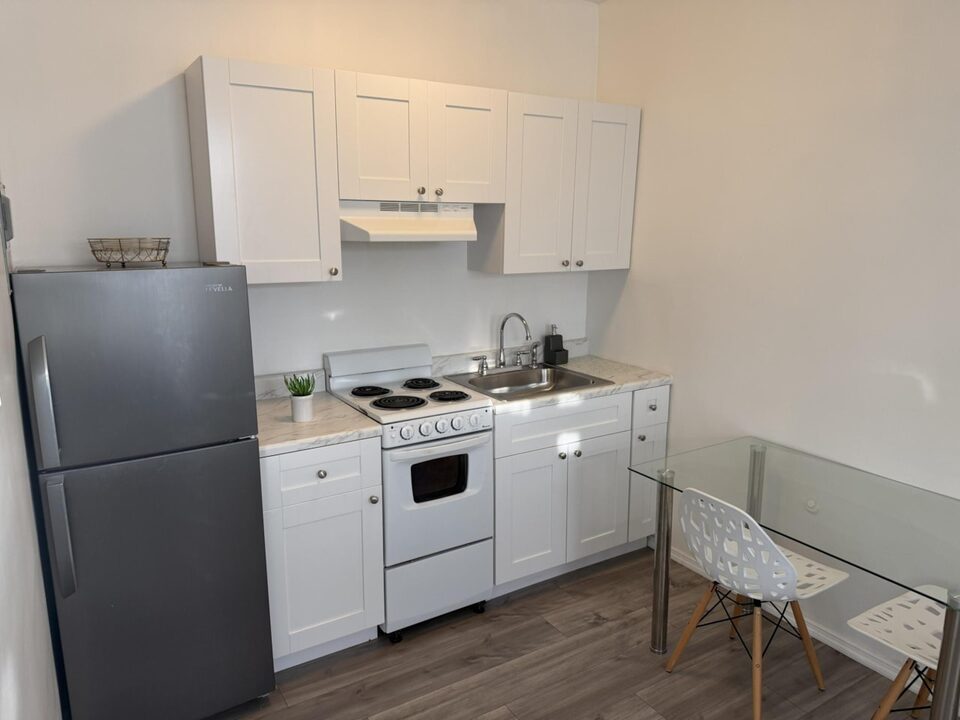 Kitchen with white cabinets, stainless steel refrigerator, electric range and a glass dining table