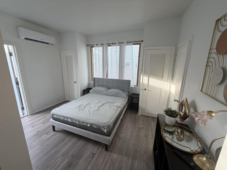 Bedroom with wood-look plank flooring and wall air conditioning unit