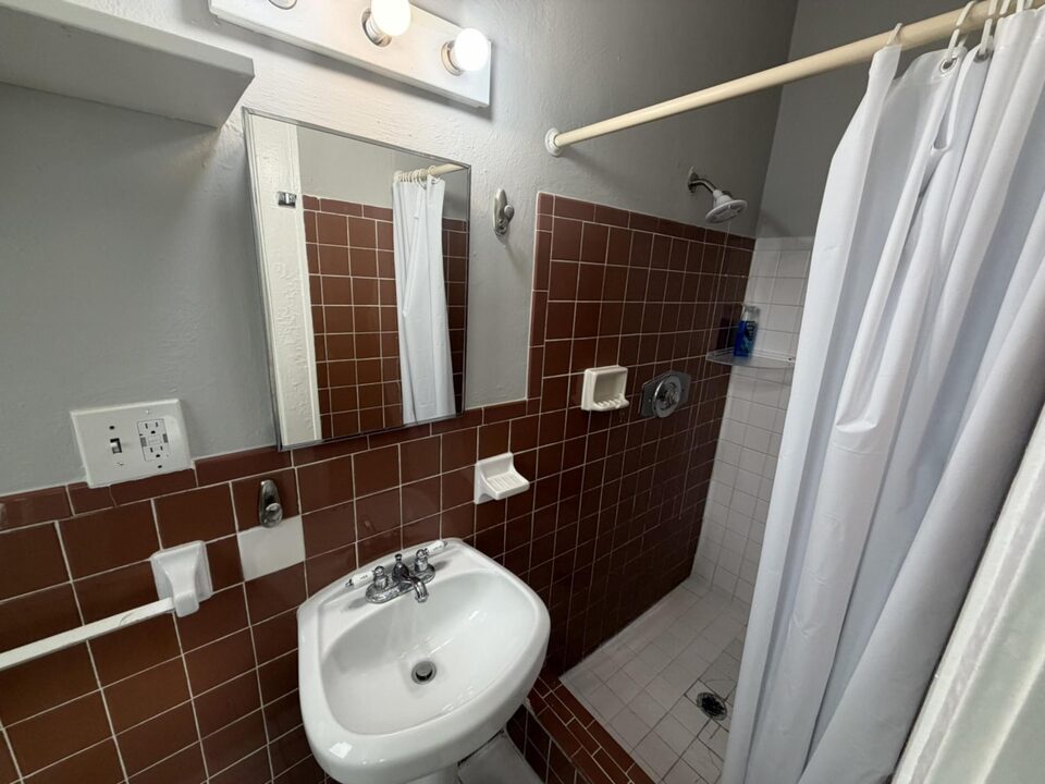 Bathroom with terracotta tile, pedestal sink and a walk-in shower