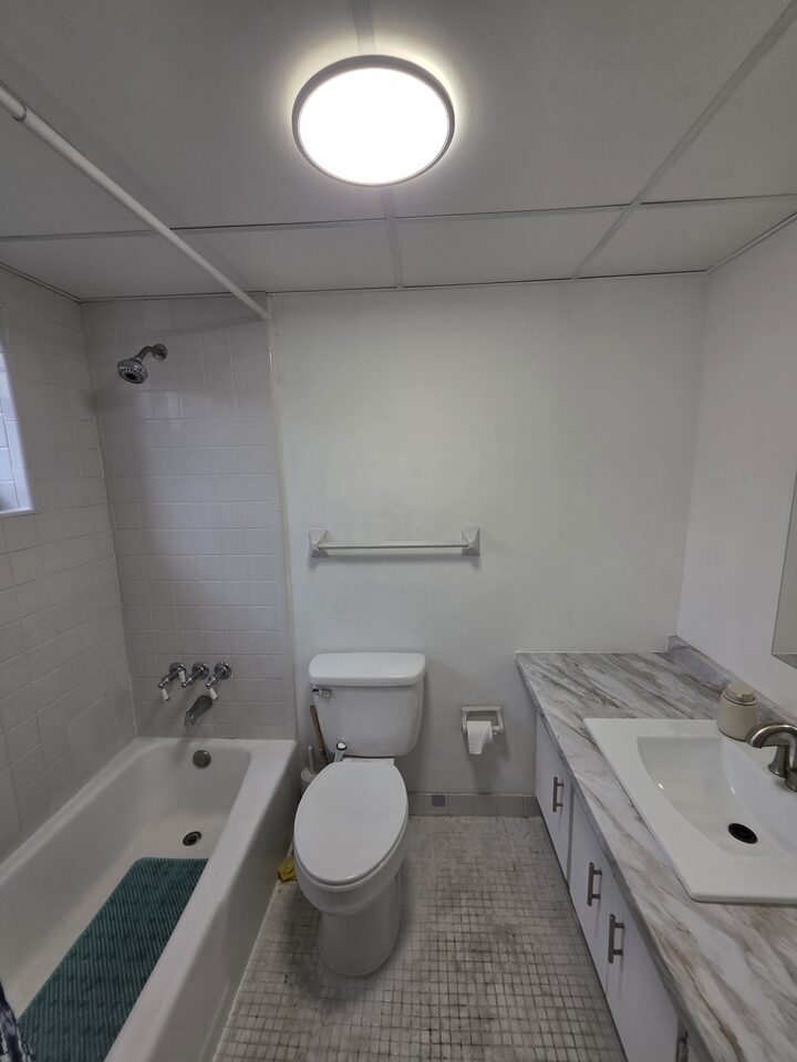 Bathroom with a tub and shower, a tiled surround, a marble-look vanity and a mosaic tile floor