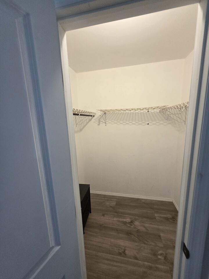 Walk-in closet seen from the doorway, with shelving and plank flooring
