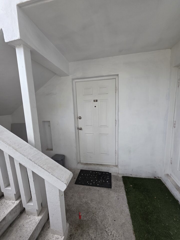 Front door of apartment 101, under the exterior stairs