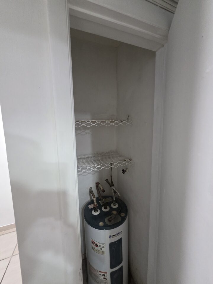 Utility closet housing the water heater, with shelving above