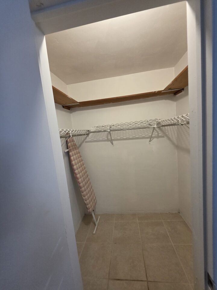 Walk-in closet with a hanging rail, a shelf and an ironing board