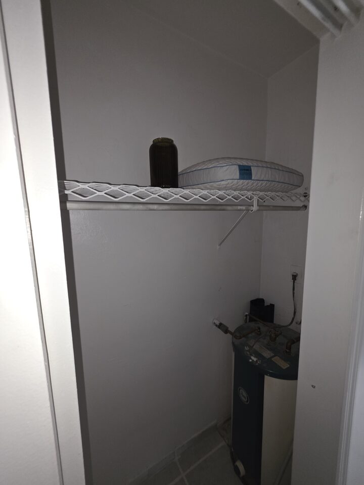 Utility closet housing the water heater, with a shelf above