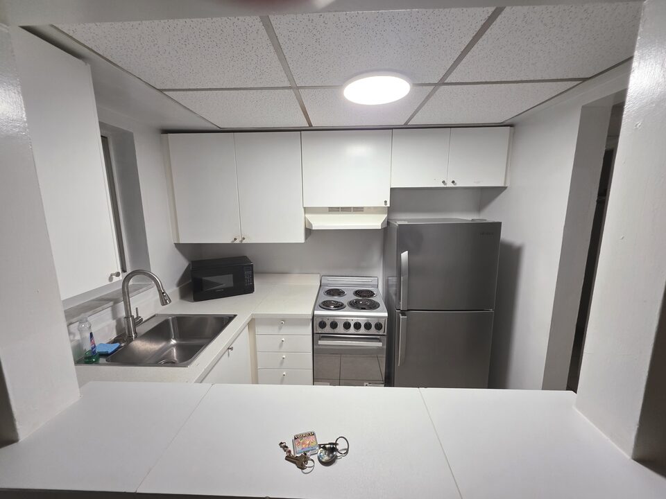 Kitchen seen from the living room pass-through, with a stainless steel sink, a microwave, an electric range and a stainless steel refrigerator