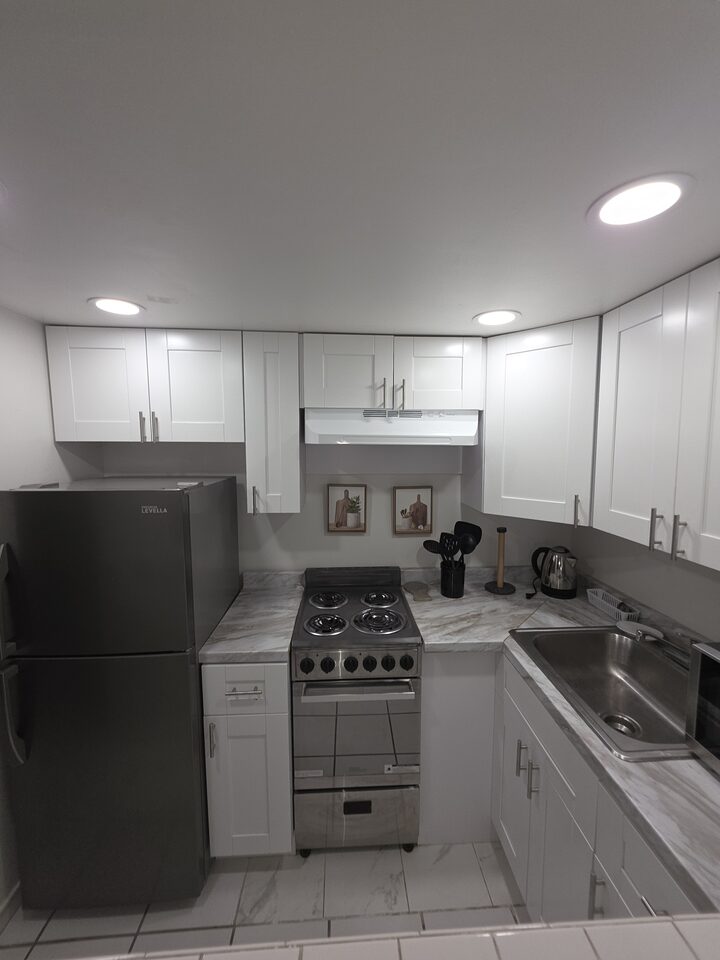 Kitchen with white shaker cabinets, a refrigerator, an electric range with an extractor hood and a marble-look countertop