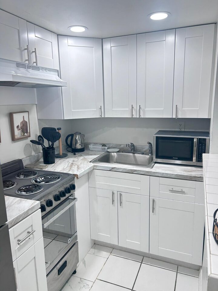 Kitchen with white shaker cabinets, marble-look countertops, stainless sink and microwave