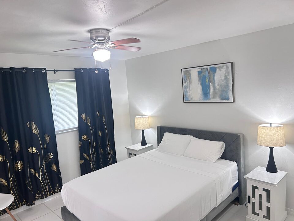 Bedroom with a queen bed, upholstered headboard, matching bedside lamps and framed artwork