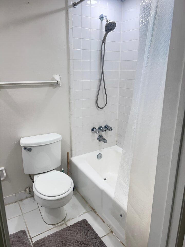 Bathroom with a full tub and shower behind a curtain