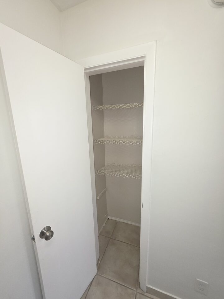 Linen closet with three wire shelves, its door standing open