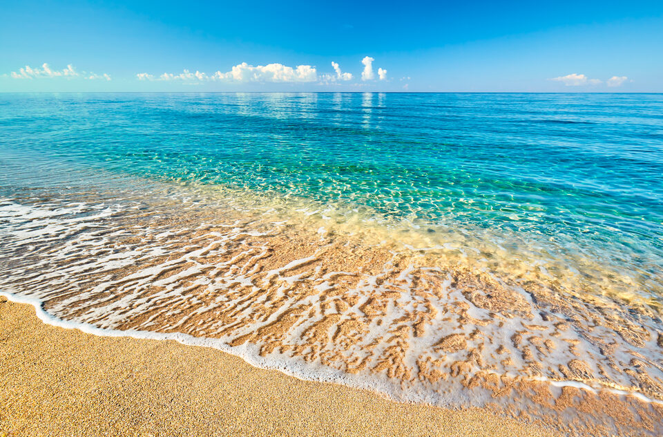A view out to sea from a tropical beach under a clear sky